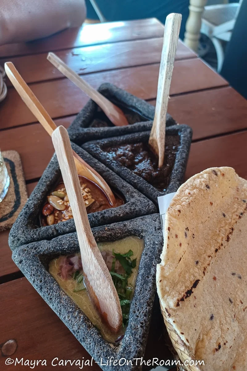 Salsas on a table served on triangular stone containers