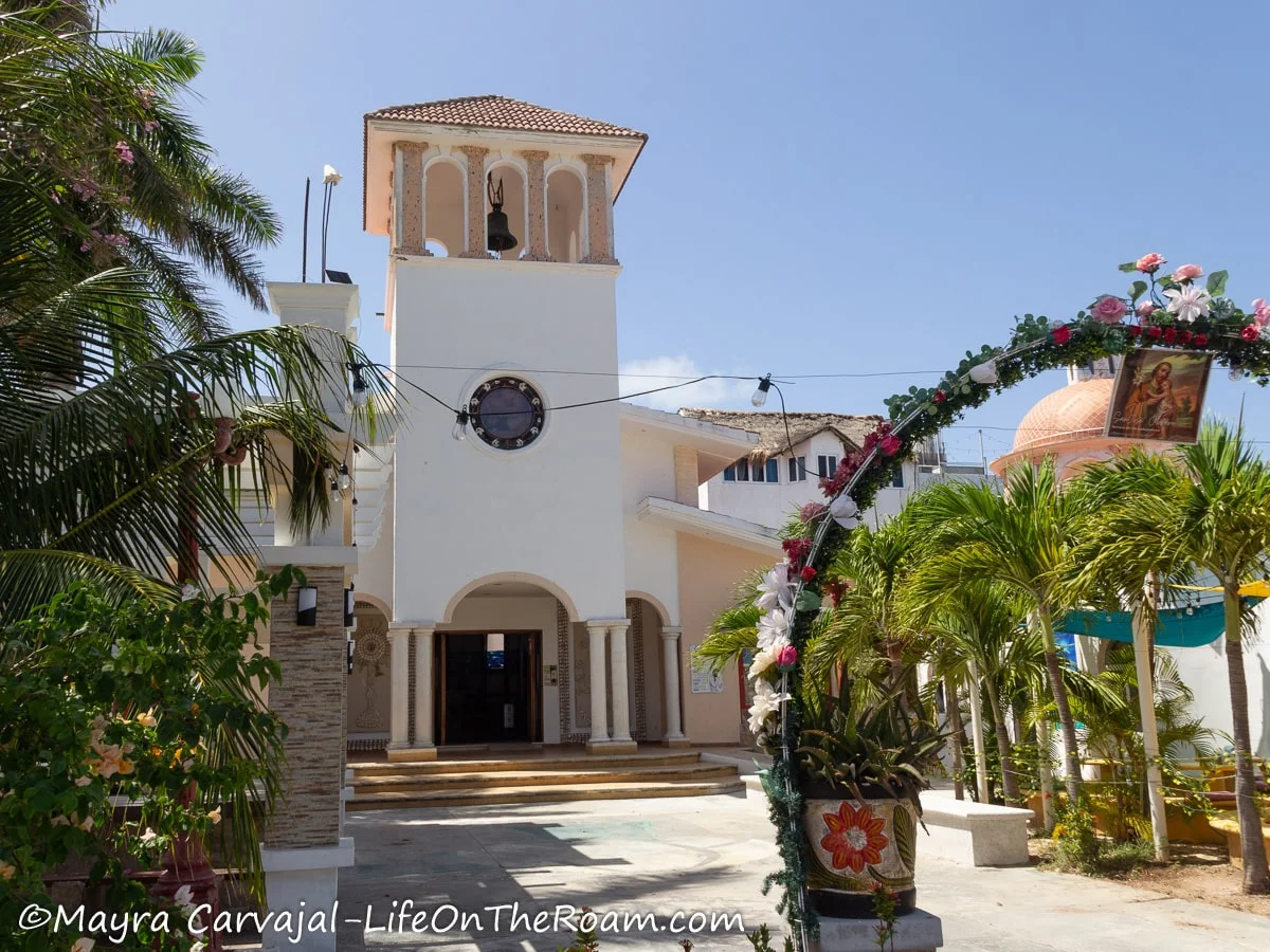 Entrance to a simple and modern church with an arch and palm trees