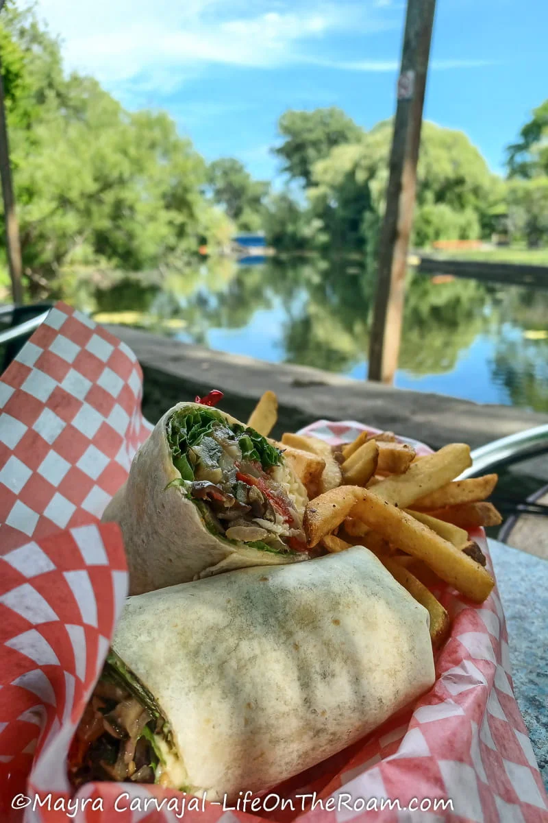 A veggie wrap with fries on a basket on an outdoor eatery