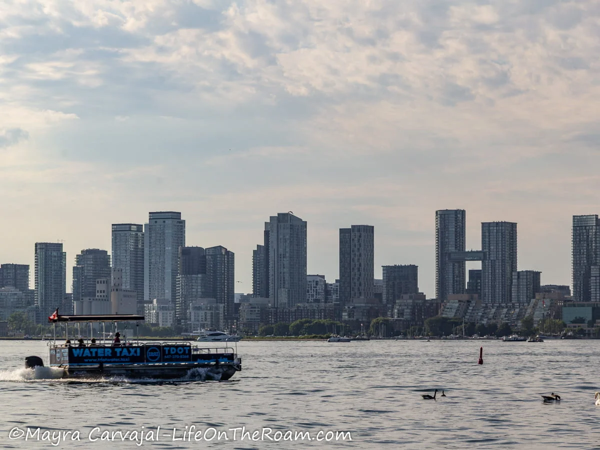 A water taxi crossing a lake with a city skyline in the distance