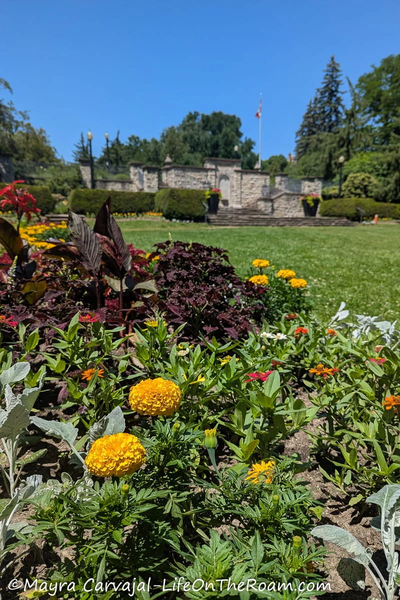 A flower bed with a stone monument in the background