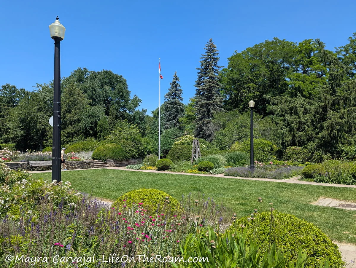 A park with flower beds on the side of a grass patch