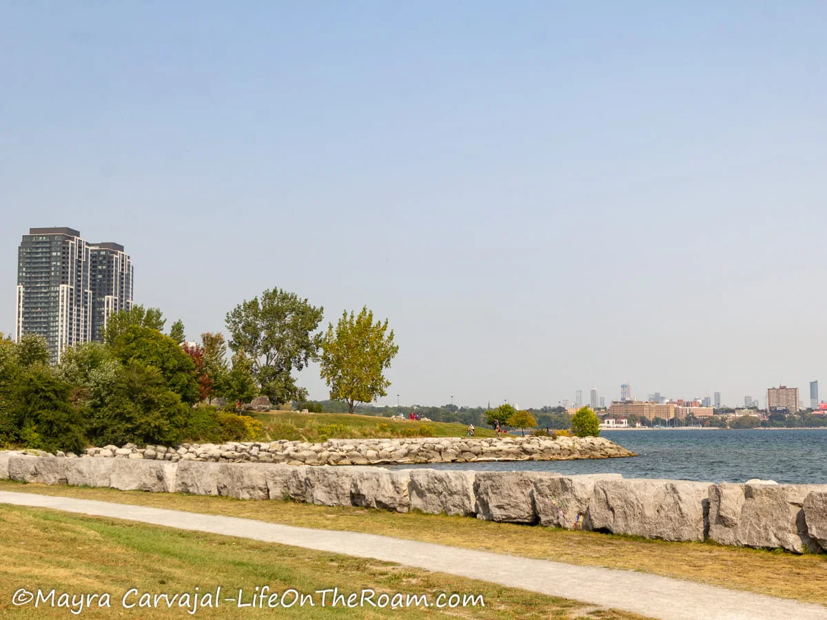 A trail along the shores of a lake with a view of a city in the distance