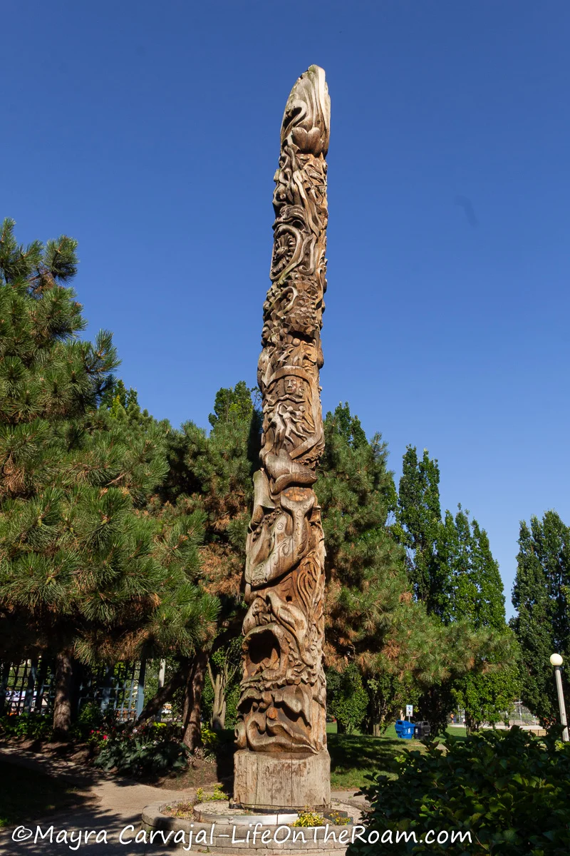 A tall totem pole with carvings of NW coast indigenous art