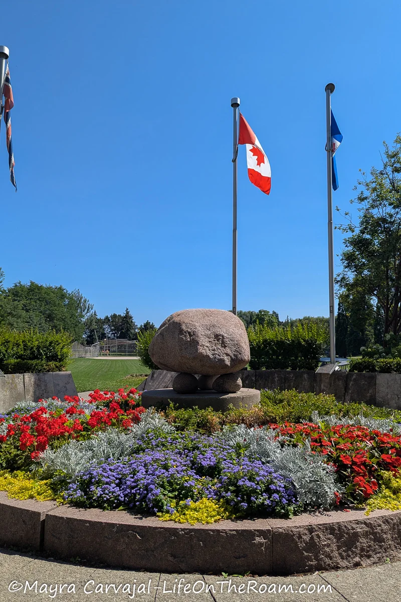 A circle with a floral landscape and a boulder in the centre, with the Canadian flag