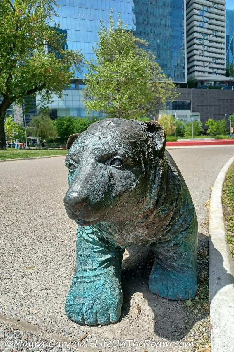 A metal sculpture of a bear in an urban park