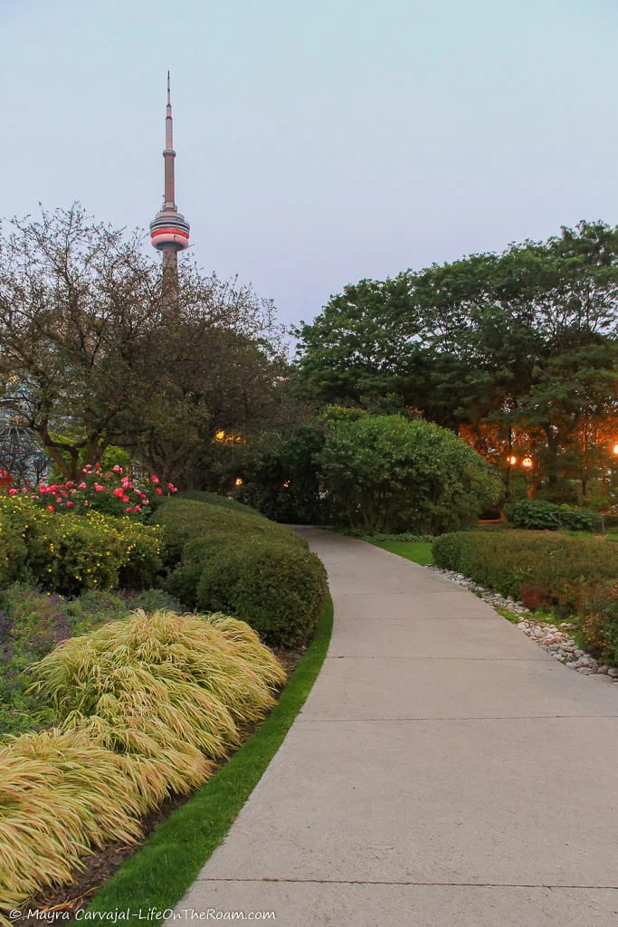 A winding path in a garden with the view of a tall freestanding tower
